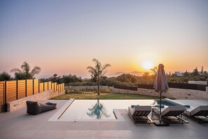 A rooftop pool area with lounge chairs and a view of the sunset over the ocean. - Kymélia Luxury Residences With Sea View (Chania)
