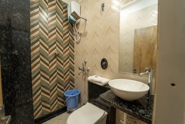 A bathroom with a herringbone patterned wall, a white sink, a mirror, and a toilet. - Hotel Park View Villa (Jodhpur)