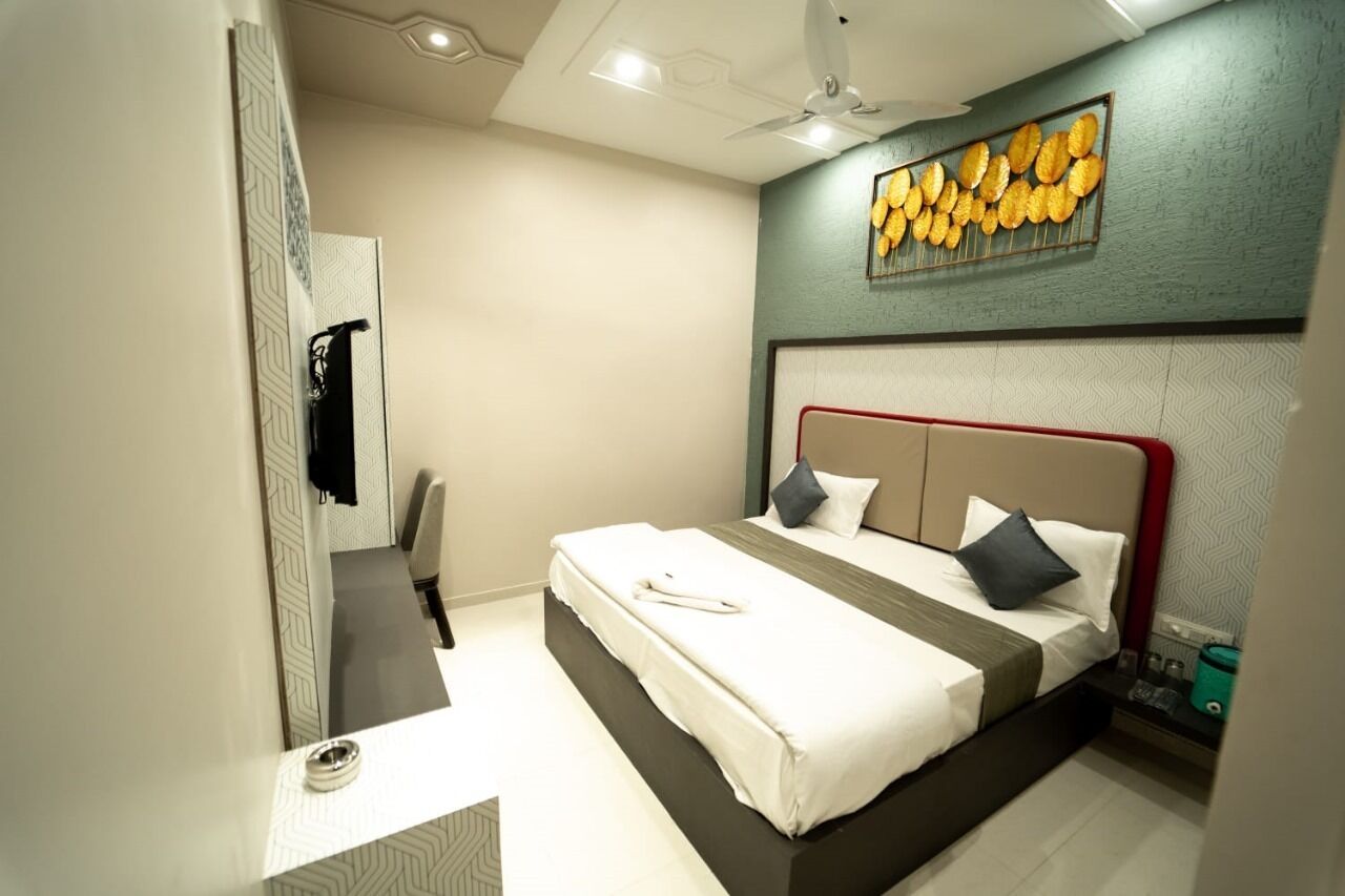 A modern hotel room with a large bed, a desk, and a wall-mounted artwork.
