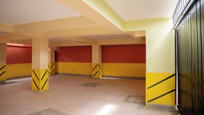 Uma garagem de estacionamento com paredes amarelas e vermelhas, marcações em formato de cunha e um portão de metal.