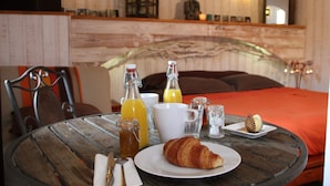 Ein Frühstücksangebot mit einem Croissant, Saft und einer Flasche auf einem runden Tisch.