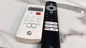 A white and a black remote control on a marble surface.