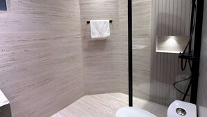 A modern bathroom with a shower enclosure, a toilet, and a towel rack.