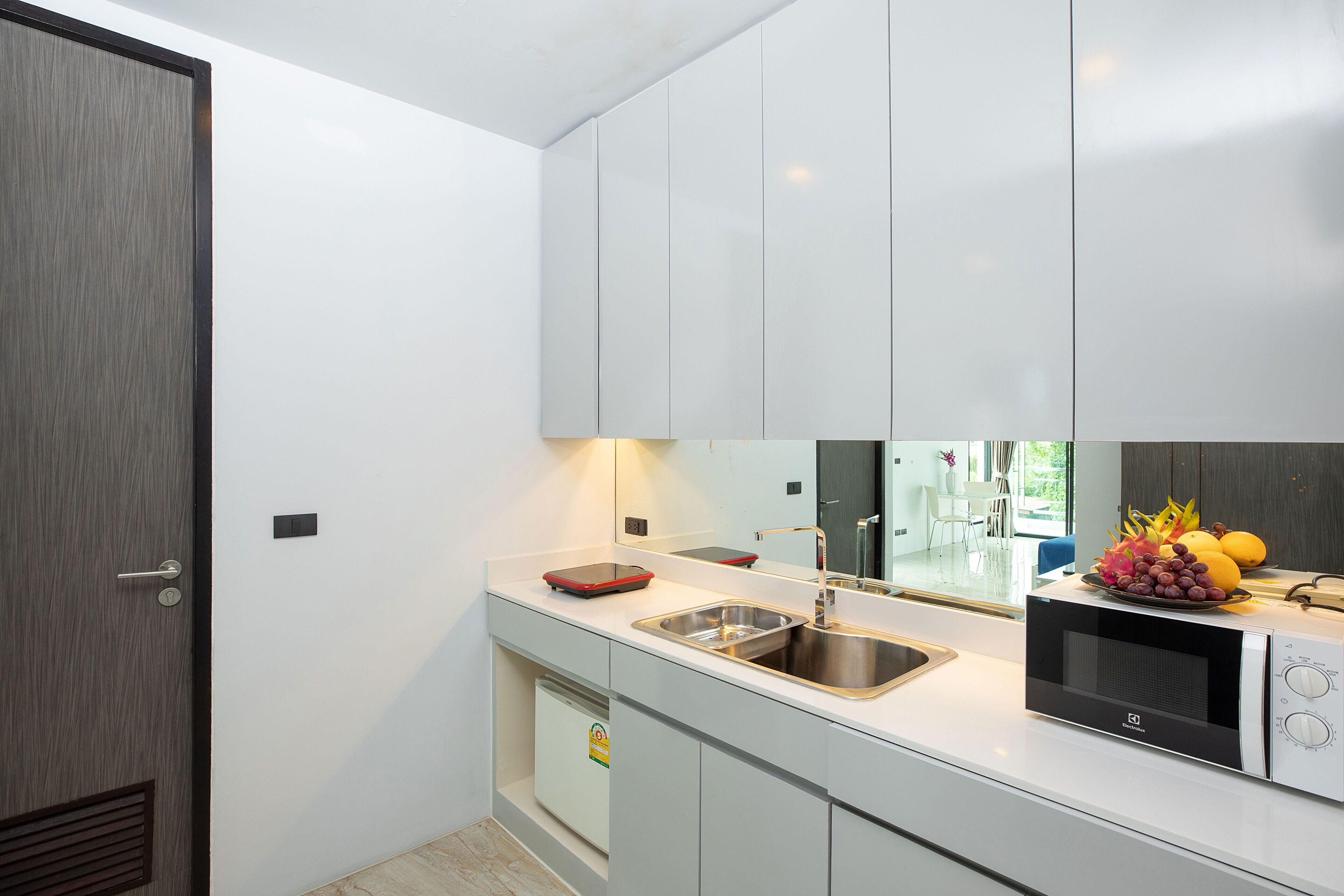 A modern kitchen with white cabinets, a stainless steel sink, and a microwave.