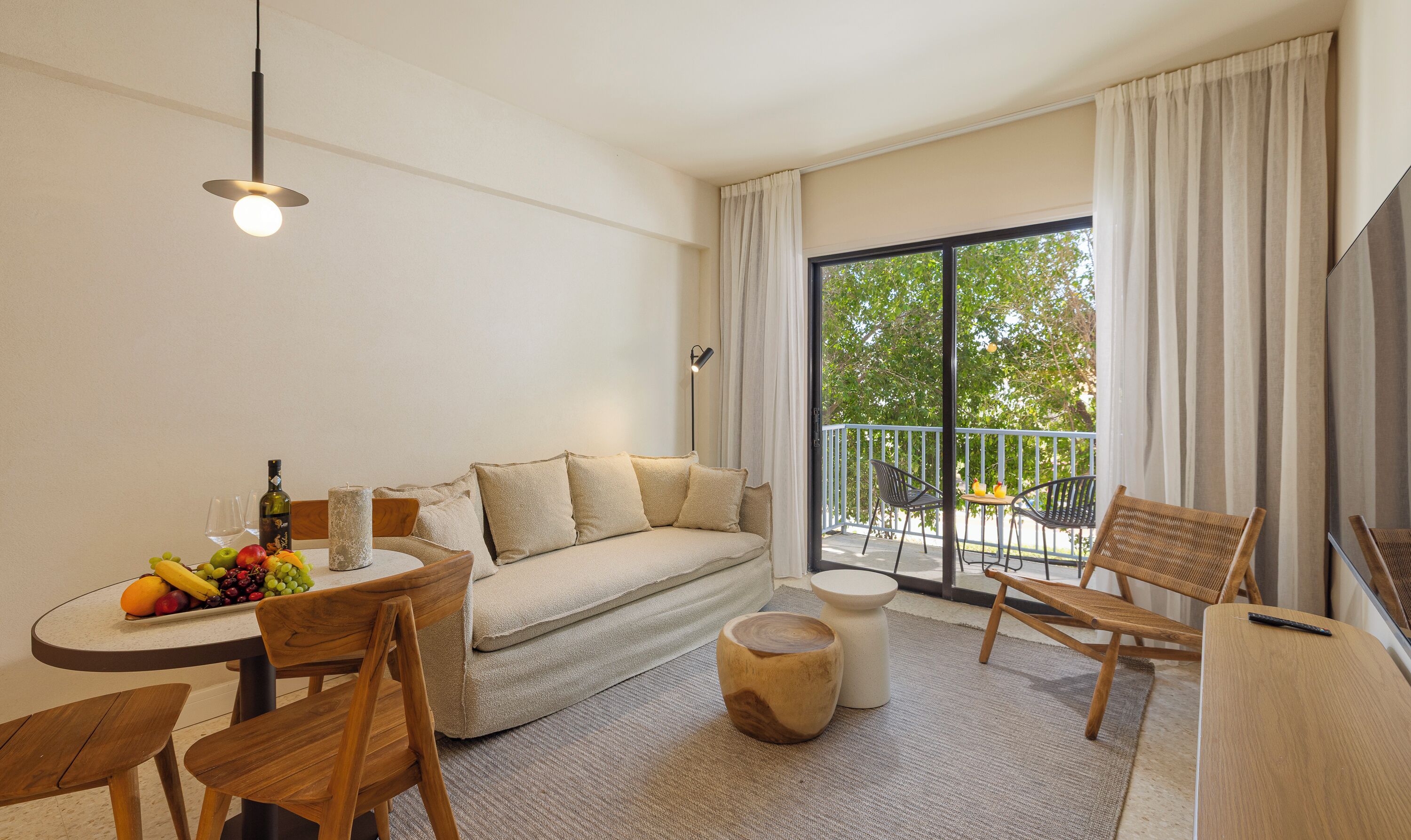 Una sala de estar moderna con sofá, mesa de comedor, sillas y un balcón con vistas.