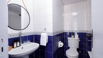 Un bagno con lavandino bianco, un water e uno specchio.