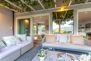 Een moderne woonkamer met twee banken, een salontafel en uitzicht op een tuin en bergen.