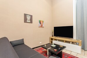 Un salon moderne avec un canapé, un téléviseur à écran plat, une table basse et des œuvres d’art accrochées au mur.