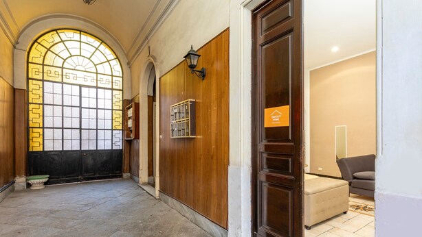 A hallway with a wooden door, a glass door with a geometric pattern, and a tiled floor. - Apartment 'Giulia's Home - Borgo' with Private Terrace, Wi-Fi and Air Conditioning (Catania)