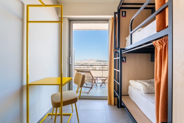 Une petite pièce comprenant un lit superposé, une petite table et une chaise.