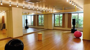 A spacious room with large windows, wooden flooring, and exercise equipment. - YellowSquare Athens (Athens)