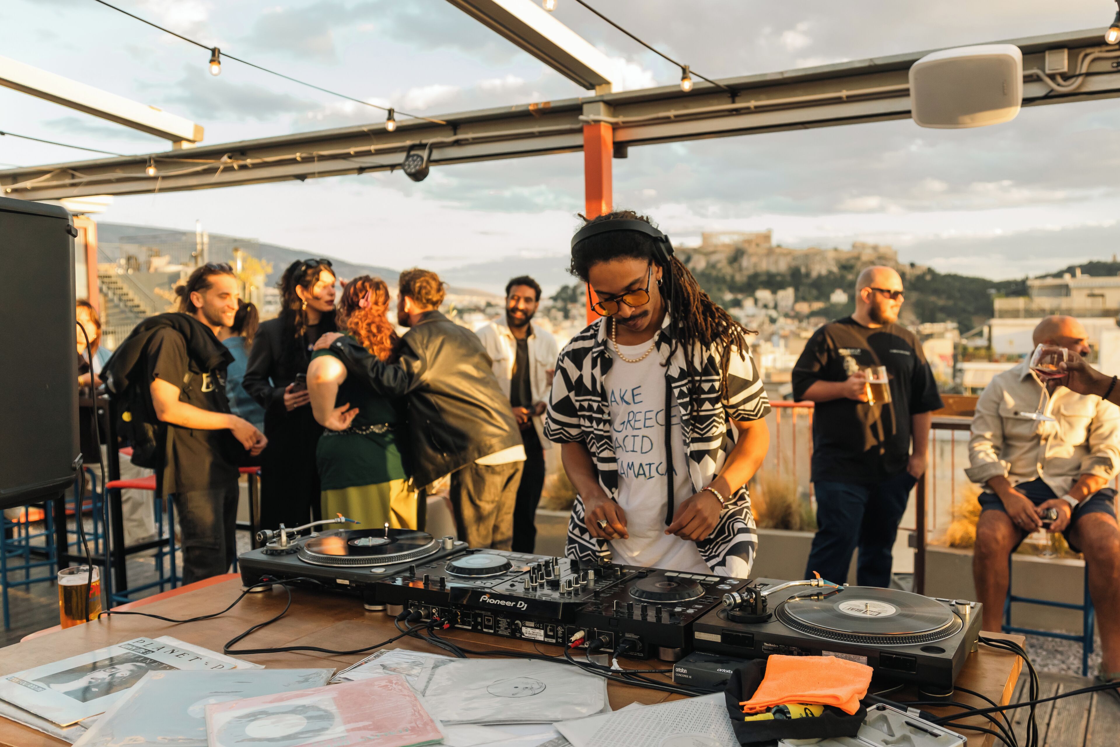 Une soirée organisée sur un toit-terrasse, avec un espace pour un DJ, des tables et des participants.