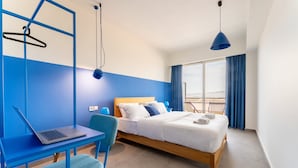 A modern hotel room with a bed, a desk with a laptop, a chair, and a view of the outdoors. - YellowSquare Athens (Athens)
