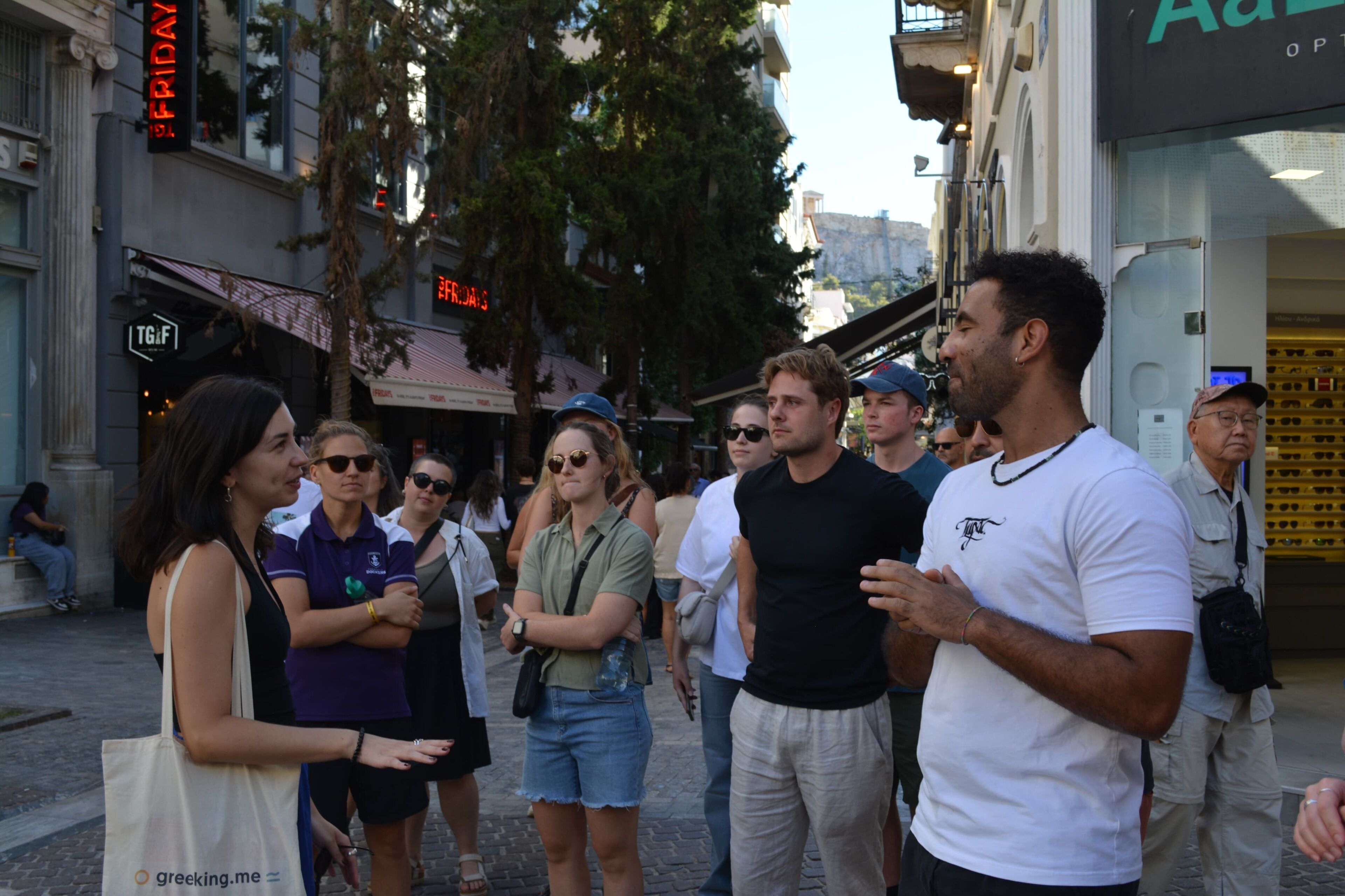 A group of people standing on a city street, engaged in conversation.