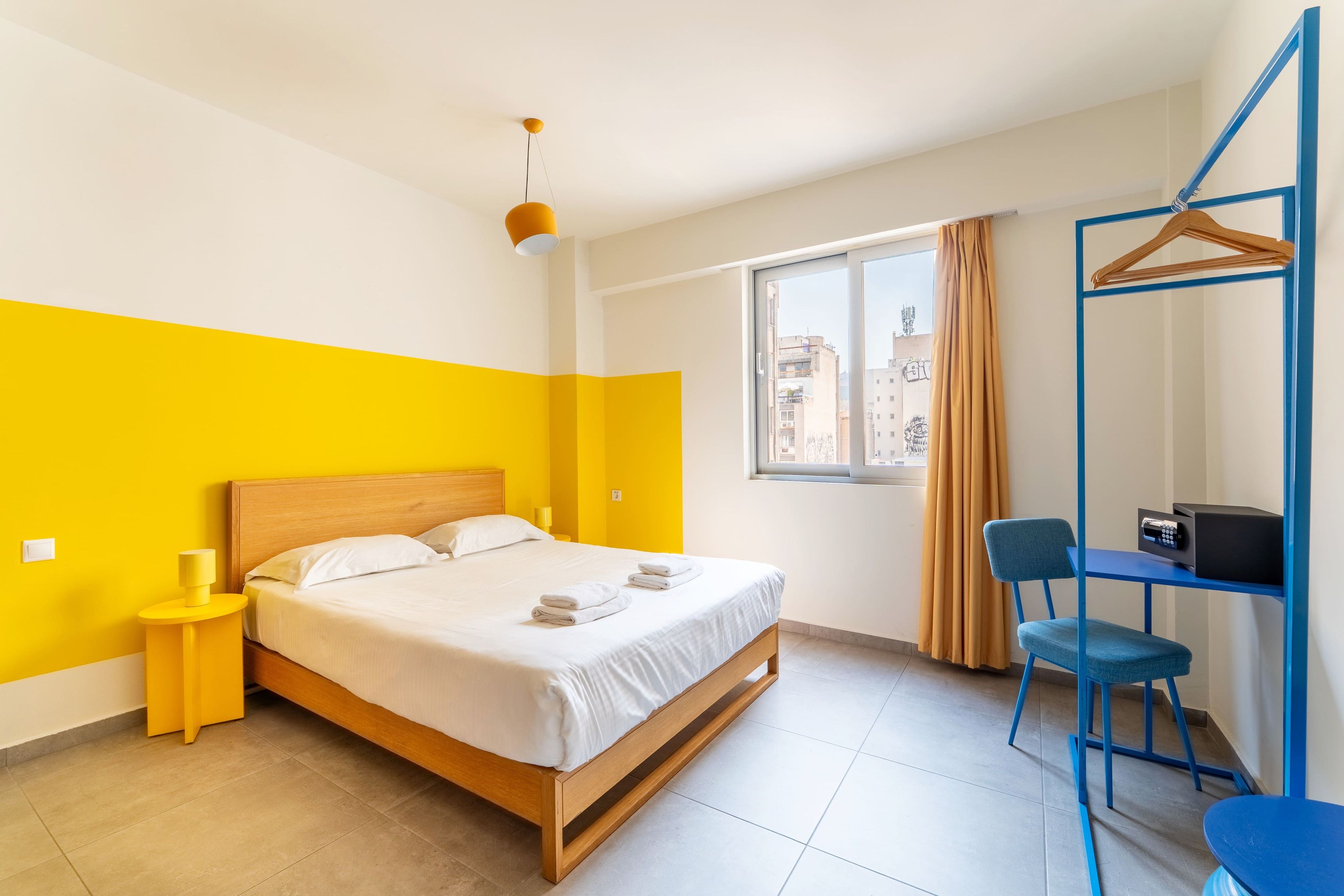 A hotel room with a bed, a desk, a chair, and a window with curtains.