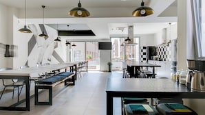 A modern kitchen with a large island, pendant lighting, and a view to the outside. - YellowSquare Athens (Athens)