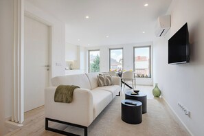 Un salon moderne avec un canapé, une table basse et un téléviseur fixé au mur.