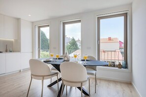 Un coin repas avec une table dressée pour quatre personnes, de grandes fenêtres et une vue sur l’extérieur.