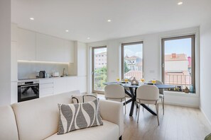 Un appartement moderne comprenant une cuisine, un coin repas et un canapé agrémenté d’un coussin à motifs.