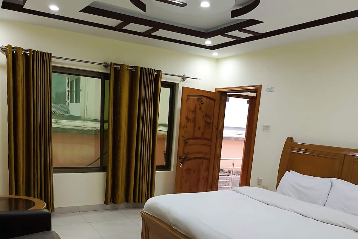 A bedroom with a wooden bed, a small round table, and curtains.
