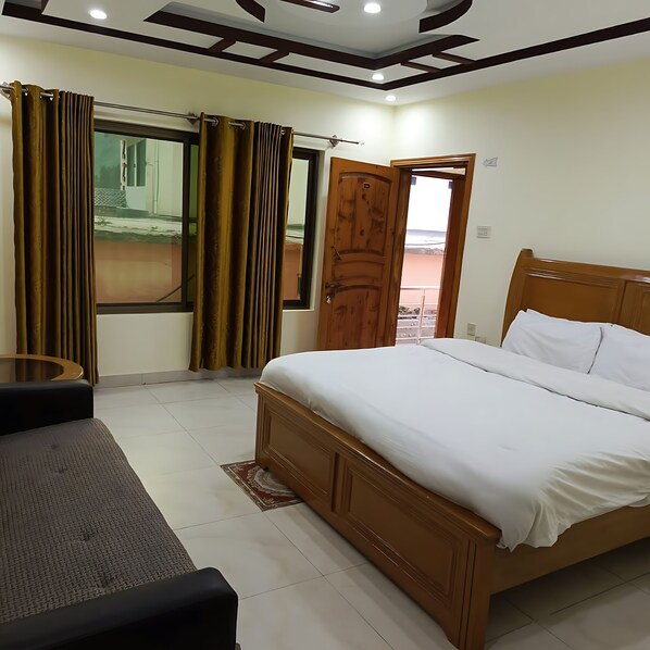 A bedroom with a wooden bed, a small round table, and curtains. - Moon Lodges Naran (Naran)