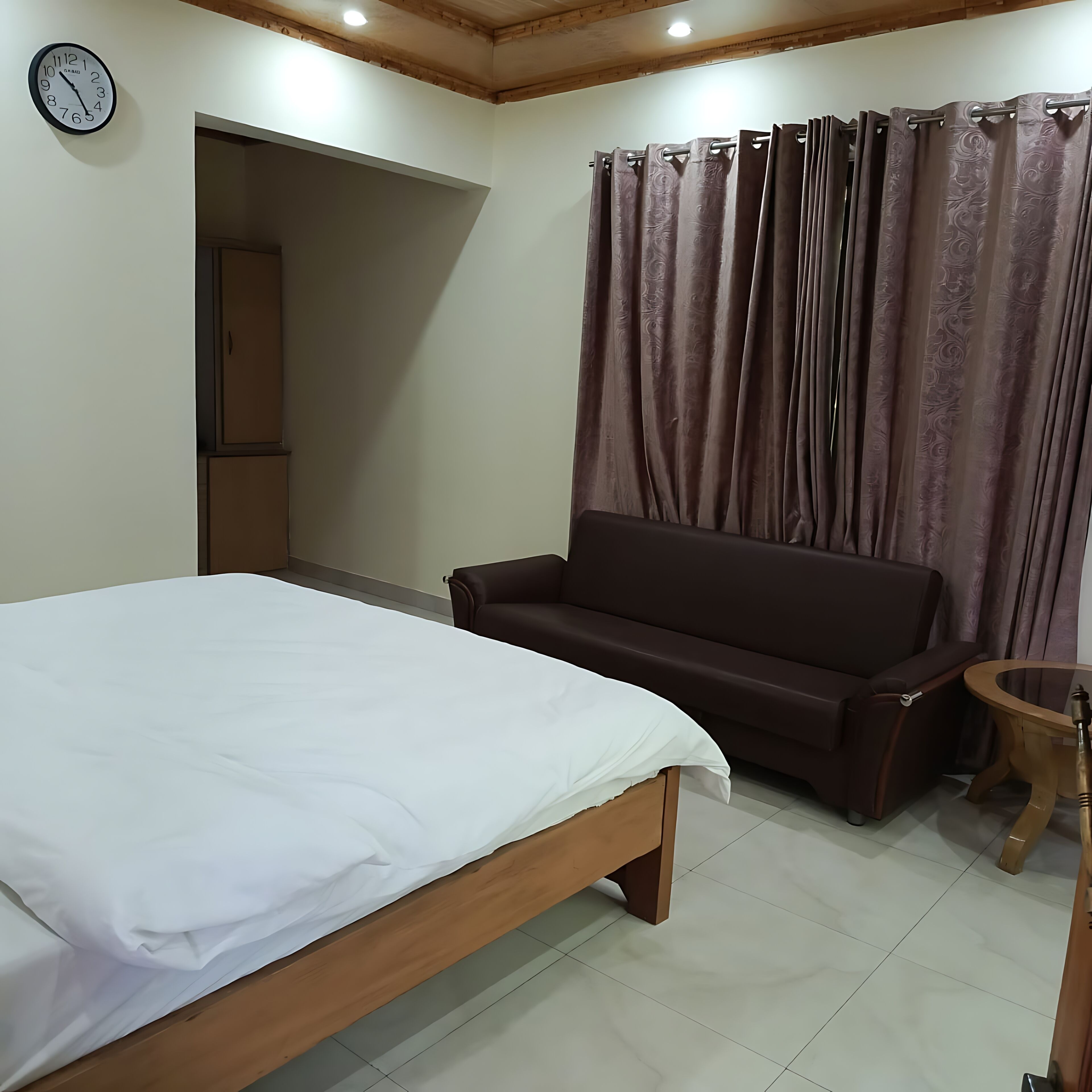Un dormitorio con cama, sofá, una mesita y cortina.