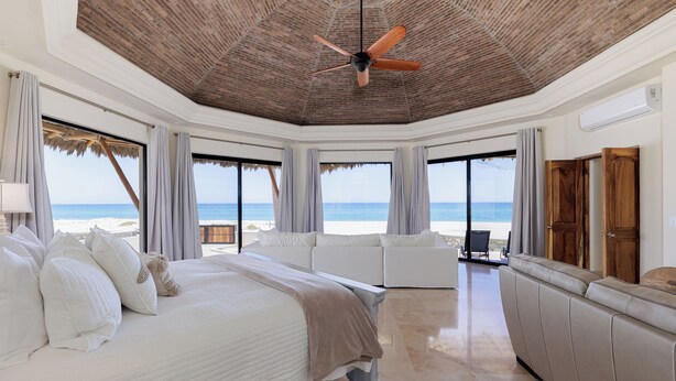 Un dormitorio amplio con una cama grande, ventilador de techo y vista a la playa.