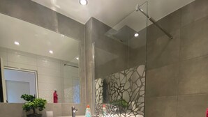 Een moderne badkamer met een douchecabine van glas, een wit wastafelmeubel en een toilet.