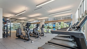 A modern gym with treadmills, elliptical machines, and weightlifting equipment.
