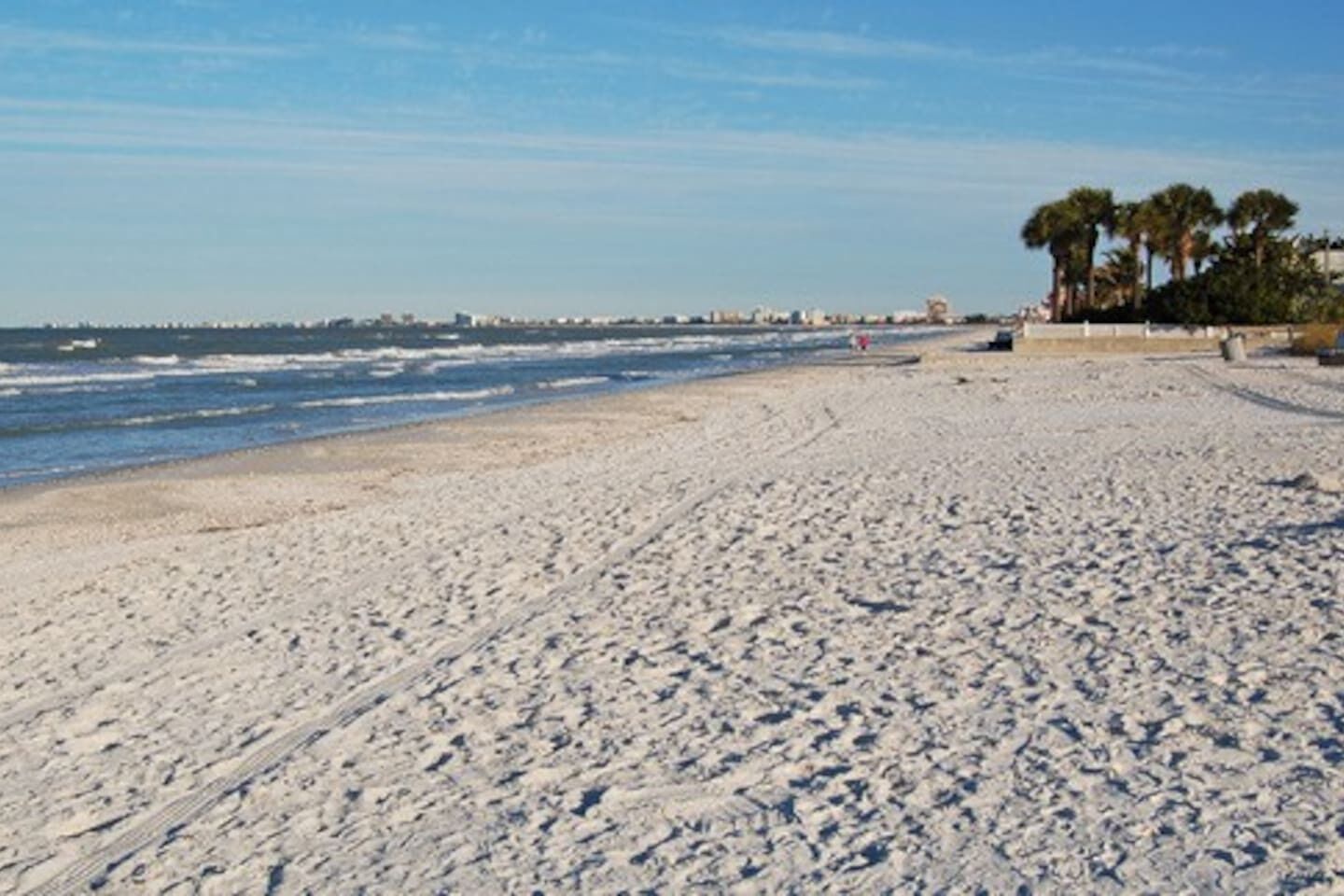 A sandy beach with a clear sky and distant cityscape.