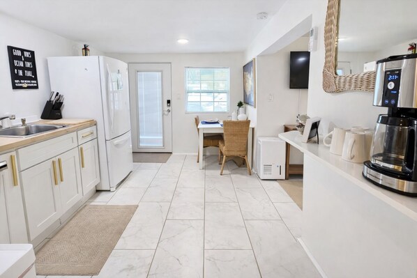 A modern kitchen with white cabinets, a built-in oven, and a coffee machine.