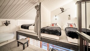 A loft bedroom with two beds, a cat tree, a deer head decoration, and a small window.
