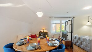 A dining area with a round wooden table set for four, blue chairs, and candles. - LubuNest3 | Terrace with barbecue & private parking space (Ludwigsburg)