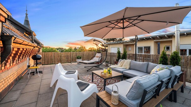A patio with a barbecue grill, outdoor seating, and a large umbrella. - LubuNest3 | Terrace with barbecue & private parking space (Ludwigsburg)