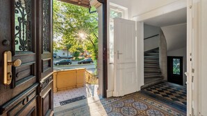 A view from a balcony with a patterned floor, a wooden door with intricate designs, and a white door leading to a staircase. - LubuNest3 | Terrace with barbecue & private parking space (Ludwigsburg)