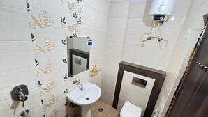 Ein Badezimmer mit Waschbecken, Toilette und Durchlauferhitzer an der Wand.