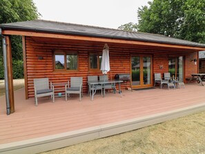 A log cabin with a patio area featuring wicker furniture, a grill, and a table with chairs. - Sunnyside Lodge (Lincoln)