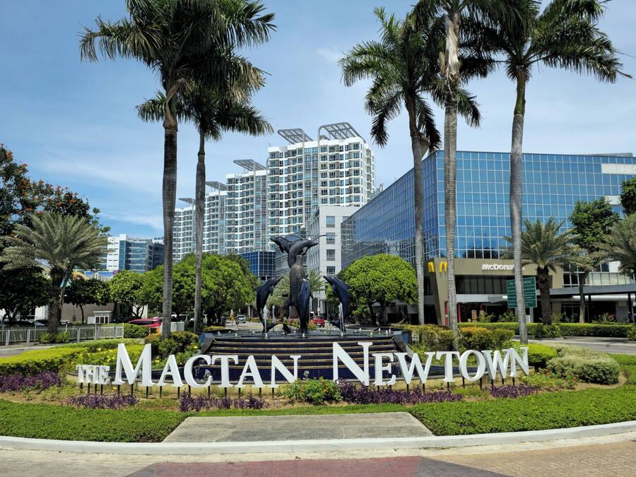 A landscaped area with a sculpture and a sign reading "The Macat Newtown."