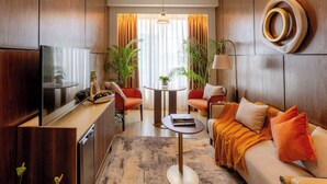 Ein modernes Wohnzimmer mit Flachbildfernseher, einer Couch, einem Couchtisch und einem Esstisch.