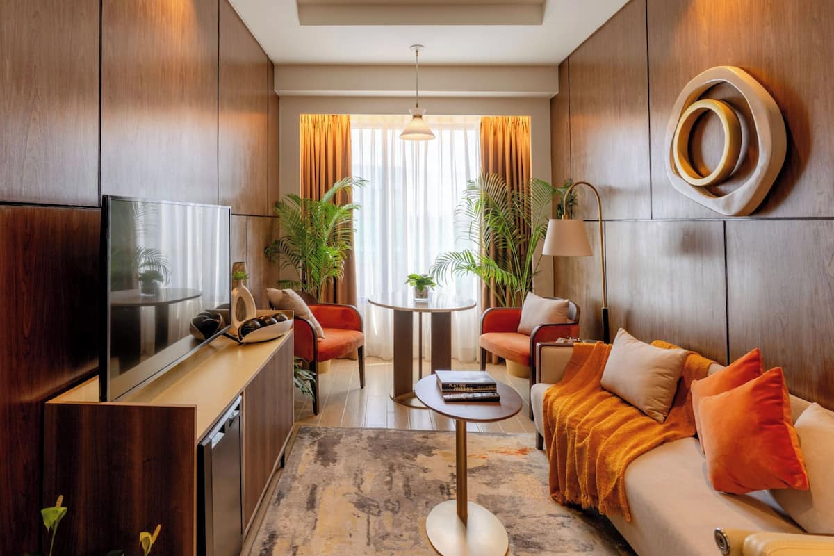 A modern living room with a flat-screen TV, a sofa, a coffee table, and a dining table.