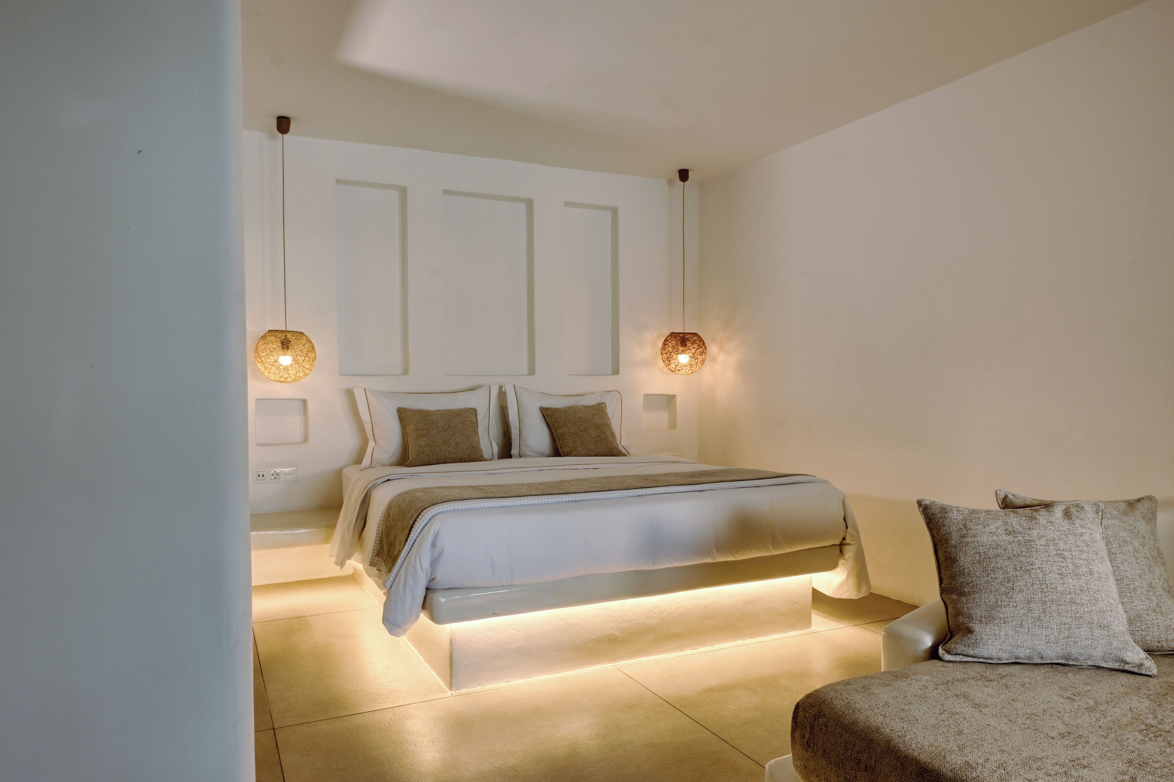 Un dormitorio con cama, mesitas de noche y lámparas de pared.