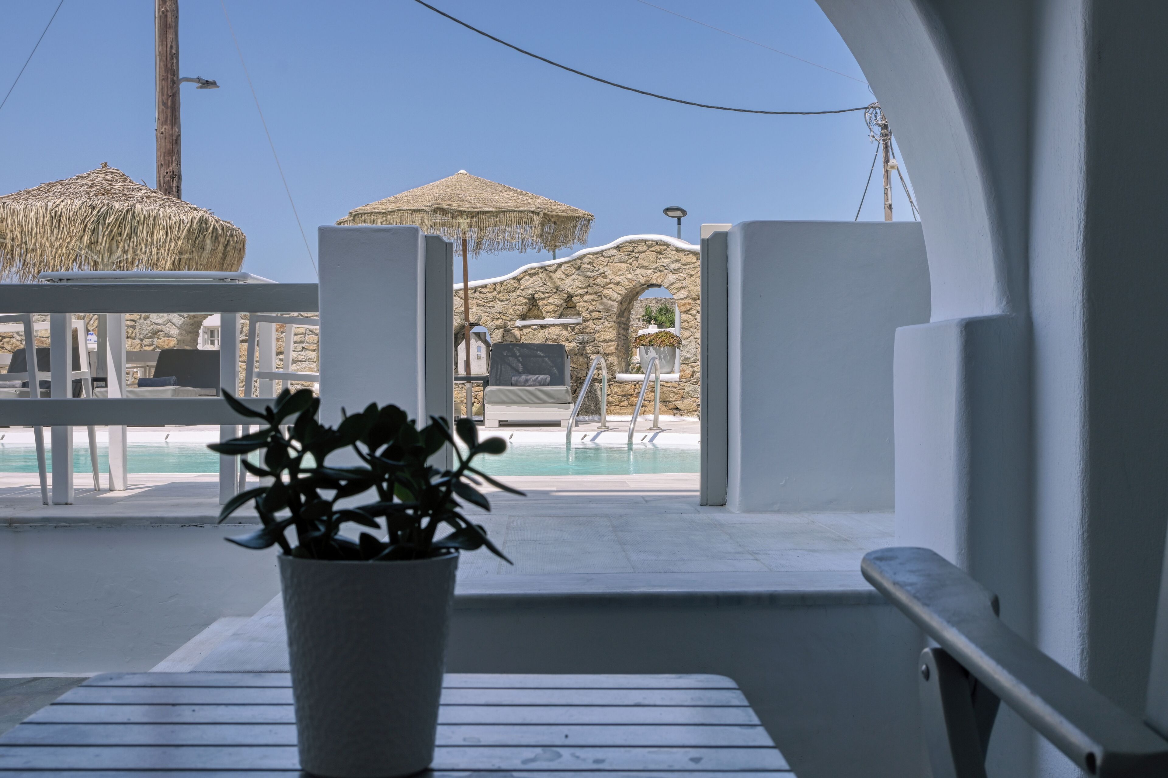 A poolside area with a thatched umbrella, a stone wall, and a view of the pool.