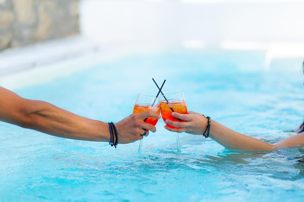Dos personas en una piscina sosteniendo vasos con bebidas.