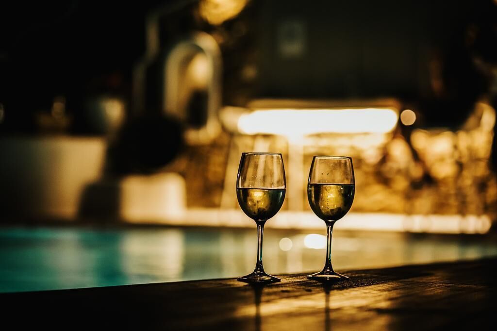 Two glasses of wine on a bar counter with a blurred background.