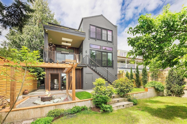 Contemporary gray facade with warm wood accents and lush greenery.