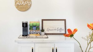 Ein Kaffee-Bereich mit einer Keurig-Maschine, einer Kaffeetasse und einem gerahmten Schild mit der Aufschrift 'living on Grace and Coffee'.