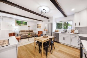 A modern kitchen with white cabinets, a wooden dining table, and a built-in oven. - Designer 1BR Oasis | 1 Min to I-5 & Costco (Lynnwood)