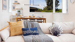 Ein gemütliches Wohnzimmer mit einer Couch, einem Couchtisch und einem Esstisch für vier Personen.