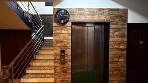 A modern interior with a staircase, an elevator, and a clock on the wall. - Indeo Residency (Kanayannur)