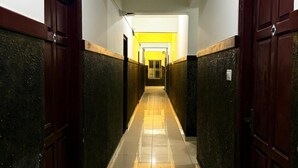 A long, narrow hallway with dark wooden doors on both sides and a tiled floor. - Indeo Residency (Kanayannur)